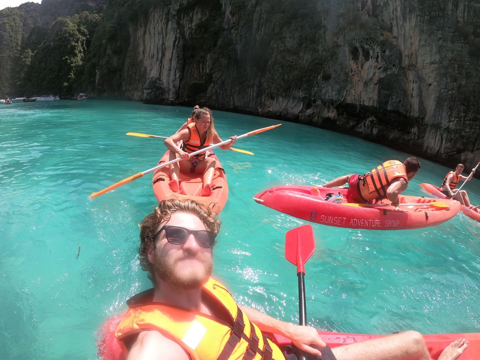 People kayaking in turquoise waters by limestone cliffs.