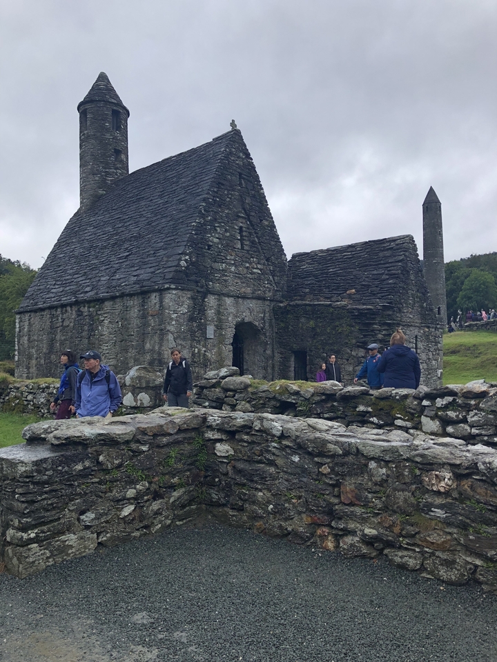 Bâtiment historique en pierre avec des personnes marchant à proximité.