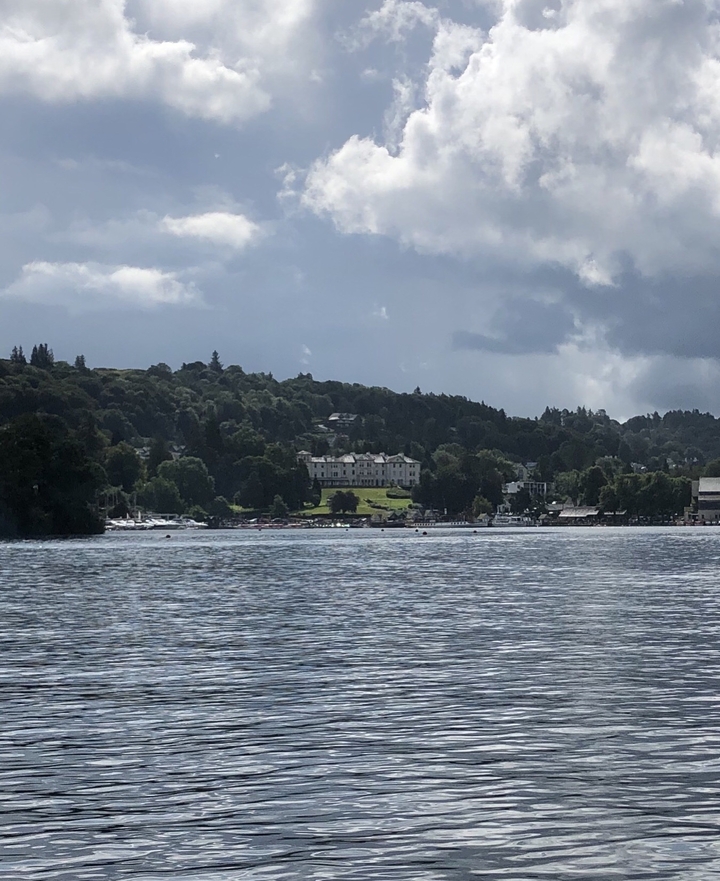 Vue panoramique d'une grande étendue d'eau avec des collines et un bâtiment au loin.