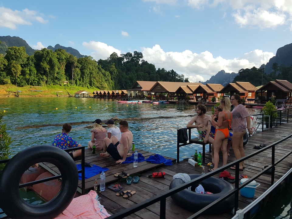Des gens profitant d'une vue au bord du lac avec des huttes flottantes.