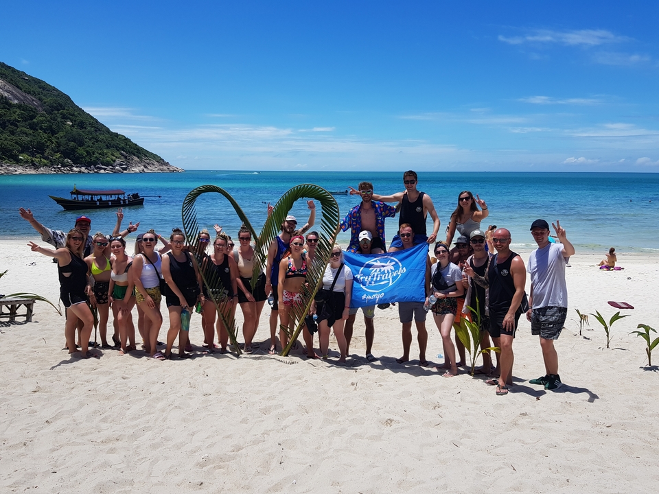 Photo de groupe sur une plage avec des feuilles de palmier décoratives.