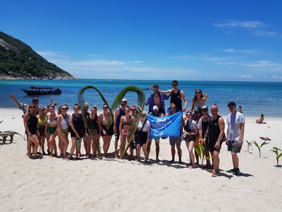 Photo de groupe sur une plage avec des feuilles de palmier décoratives.