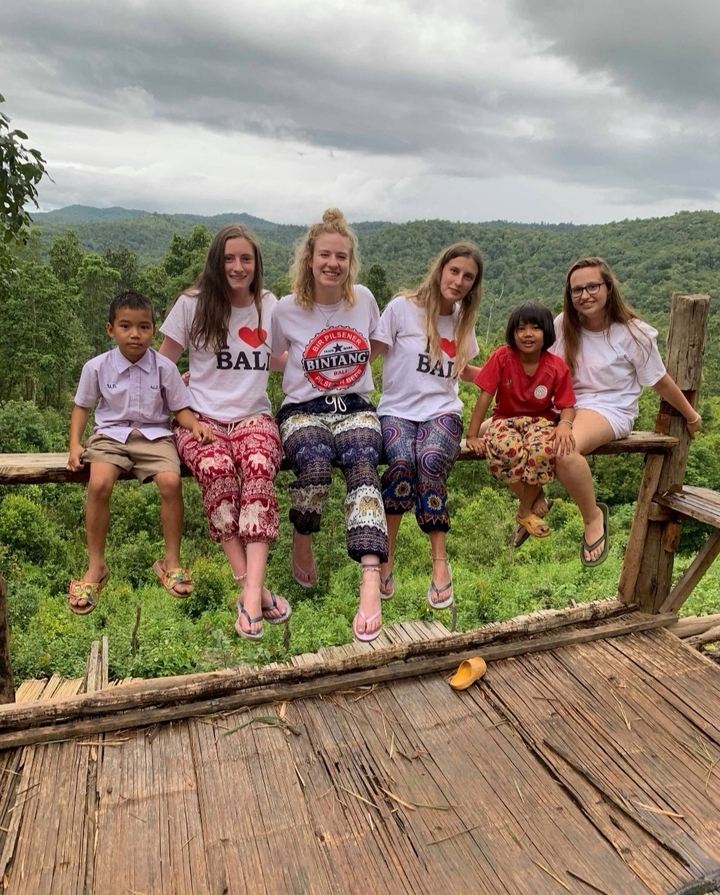 Des gens assis sur une plateforme en bois avec vue sur la forêt.