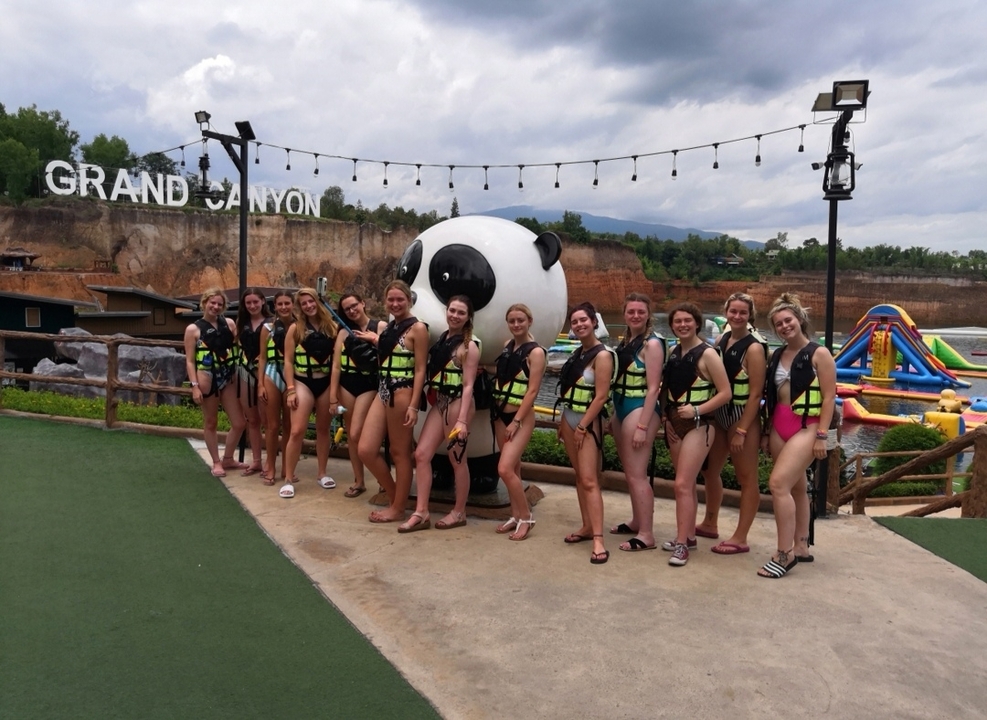 Groupe de personnes en maillots de bain posant avec une statue de panda dans un parc aquatique