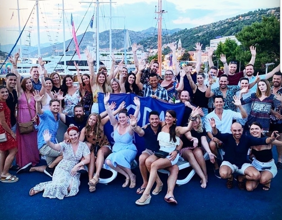 Grande photo de groupe avec des gens qui font signe de la main, prise à l'extérieur