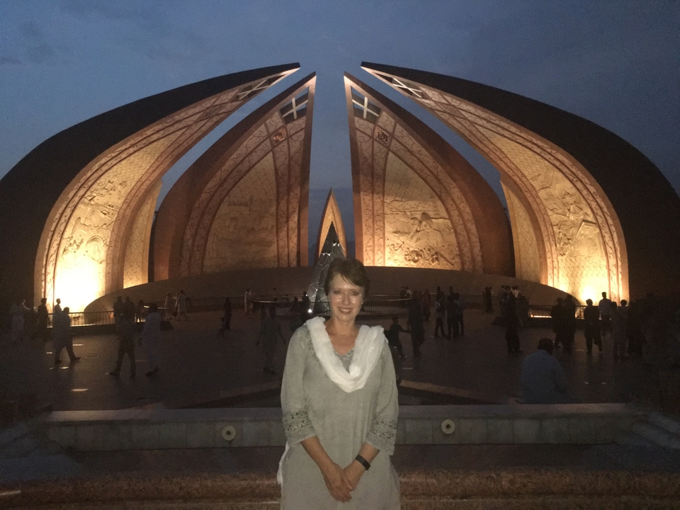 Une femme devant un monument la nuit avec des éclairages qui illuminent la structure.