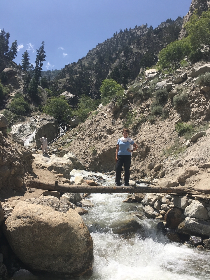 Une femme debout sur un sentier rocheux dans une région montagneuse.