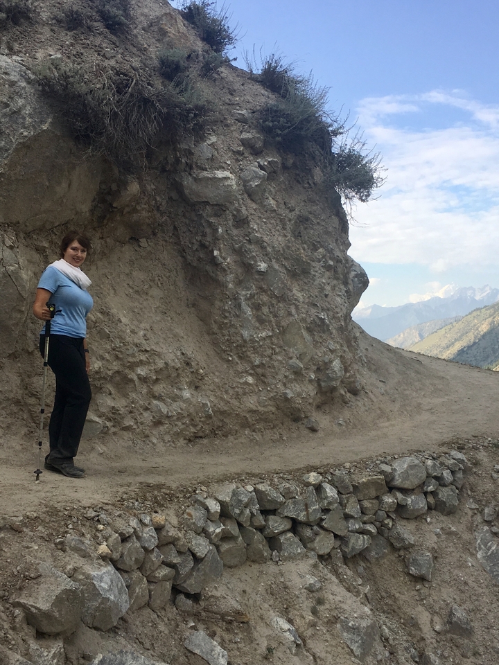 Une femme faisant de la randonnée sur un sentier de terre dans une région montagneuse.