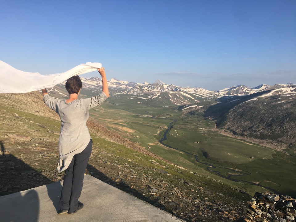 Une femme profitant d'une vue panoramique sur un vaste paysage avec des montagnes enneigées.