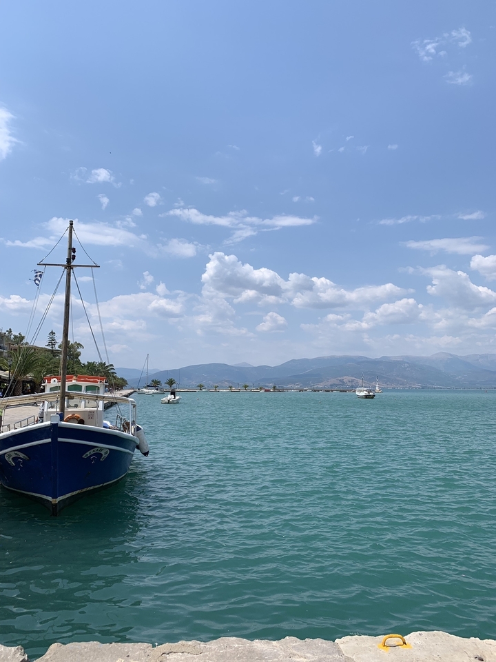 Une scène de port avec des bateaux et des montagnes en arrière-plan.
