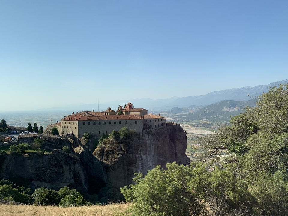 Un monastère situé au sommet d'une falaise avec des montagnes au loin.
