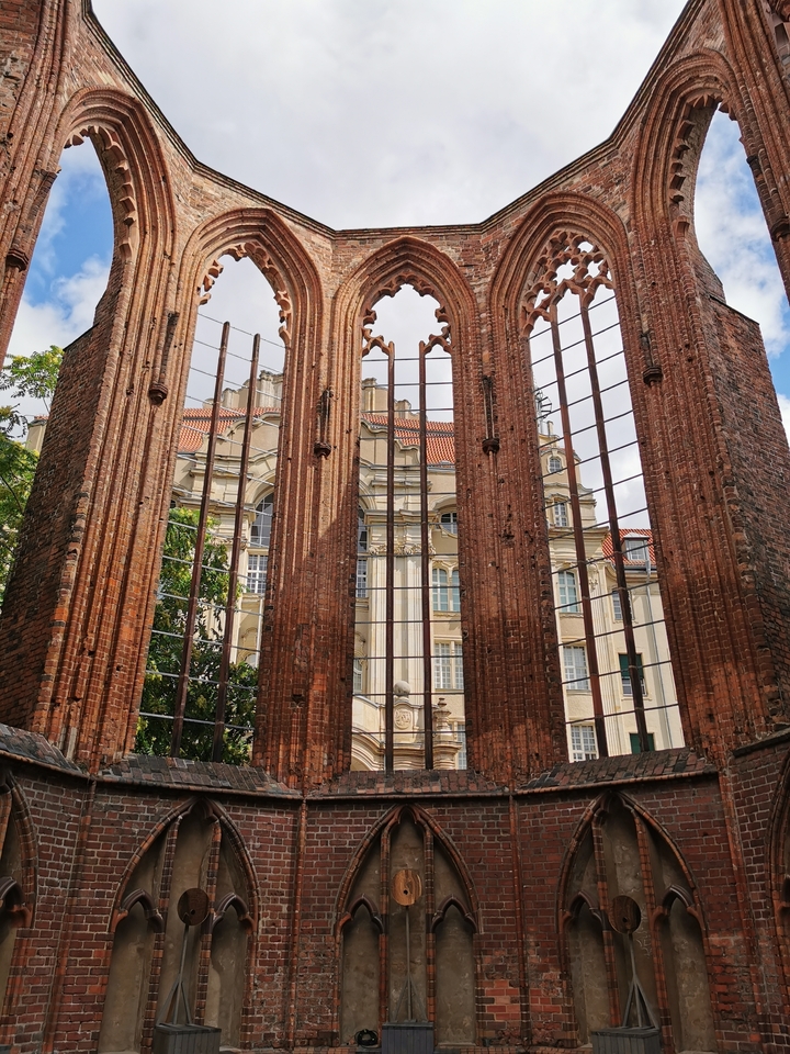 Ruines historiques en brique rouge avec des bâtiments modernes en arrière-plan.