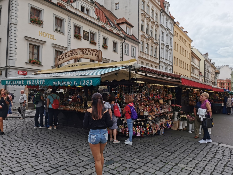 Marché de rue vendant des marchandises diverses avec des touristes qui flânent.