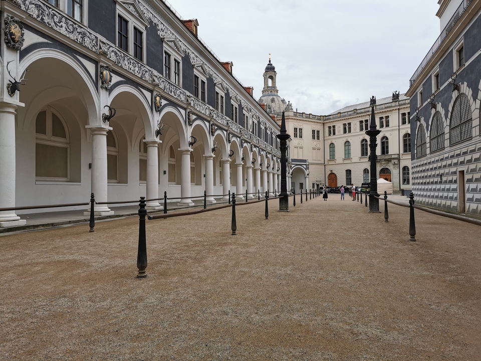 Cour avec colonnes et dôme de cathédrale au loin.