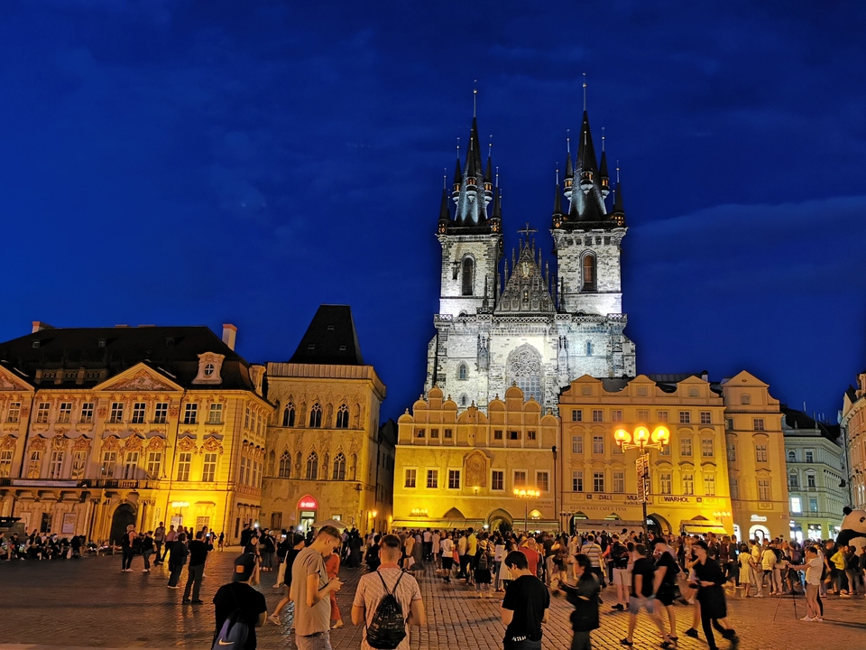 Une place animée avec une église gothique la nuit.