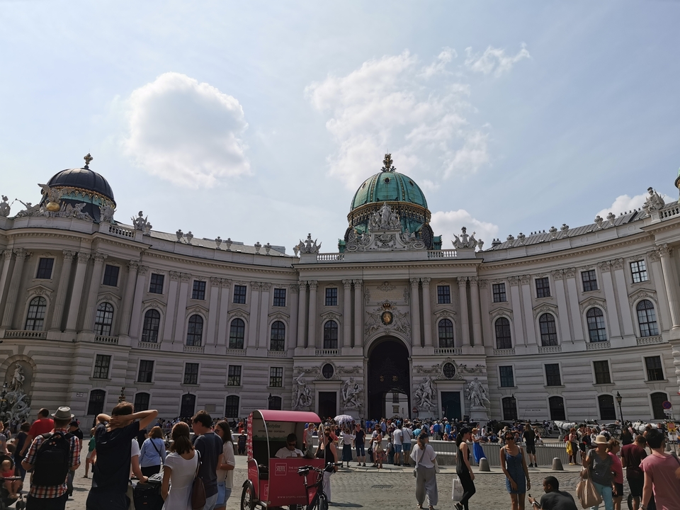 Un grand palais avec une cour remplie de touristes.