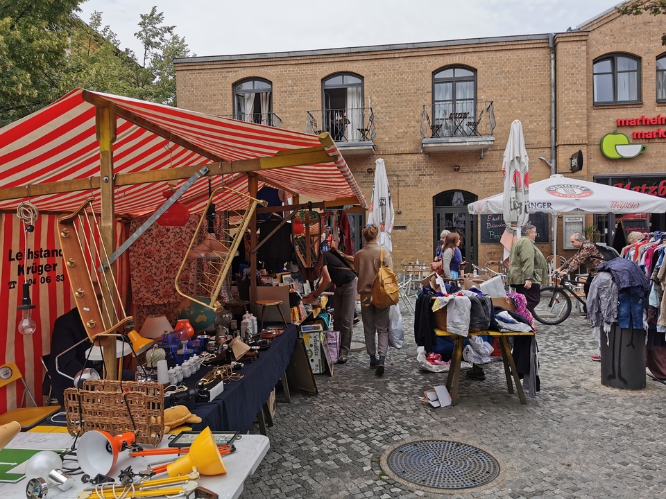 Marché aux puces avec divers étals et visiteurs.