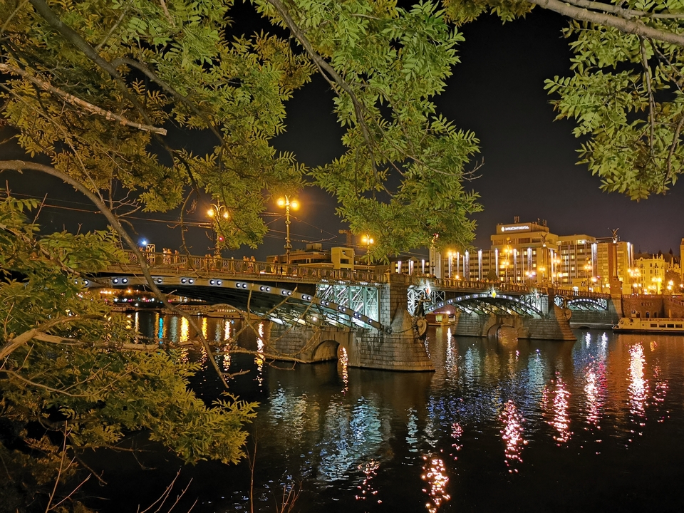 Un pont illuminé se reflétant sur une rivière la nuit.