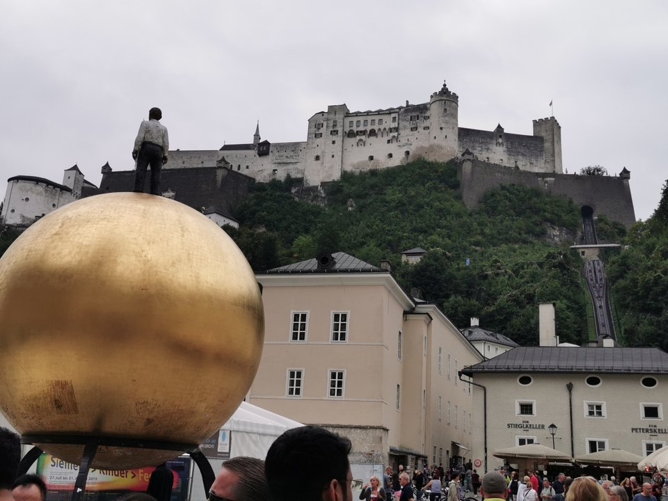 Une forteresse au sommet d'une colline avec une statue au premier plan.