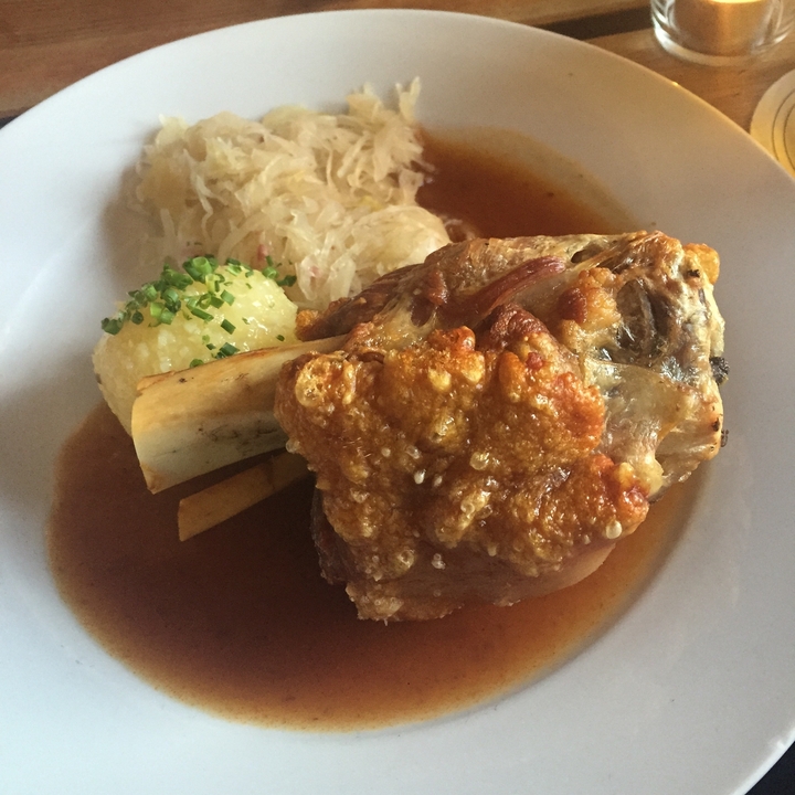 Gros plan d'un jarret de porc rôti sur une assiette avec de la choucroute et des boulettes.