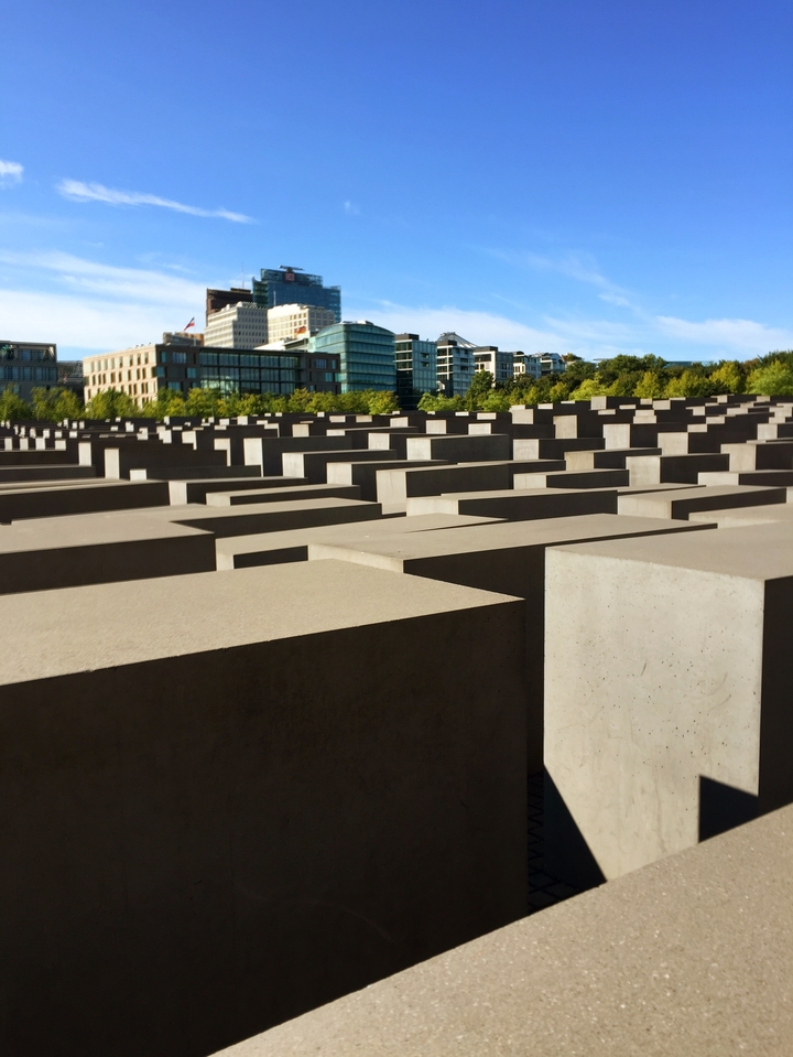 Vue du Mémorial de l'Holocauste à Berlin, avec des dalles de béton de différentes hauteurs et les bâtiments environnants.