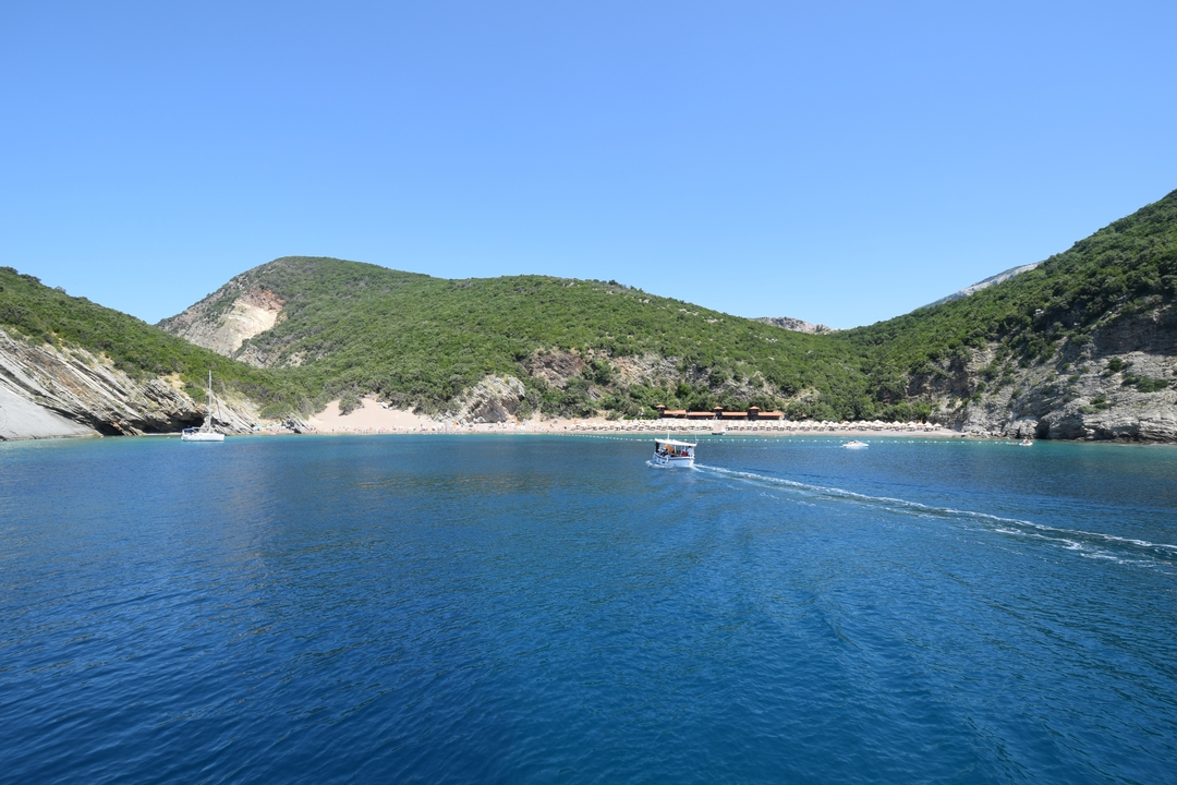 Bateau naviguant à travers des eaux bleues entouré de collines verdoyantes.