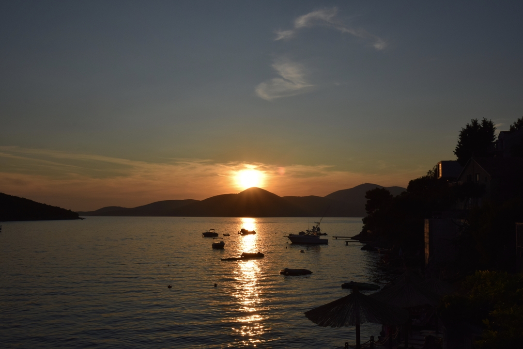 Vue du coucher de soleil sur un plan d'eau calme avec des bateaux à l'ancre.