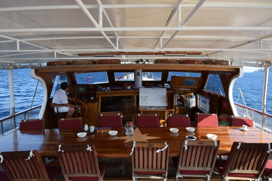 Homme sur le pont d'un bateau qui barre en mer.