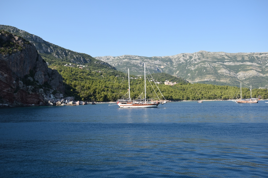 Voilier sur un plan d'eau serein avec vue sur les montagnes.