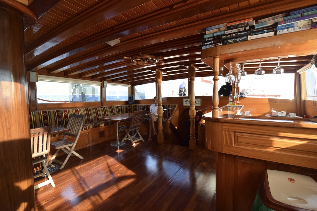 Intérieur d'un bateau en bois avec des sièges et un bar.