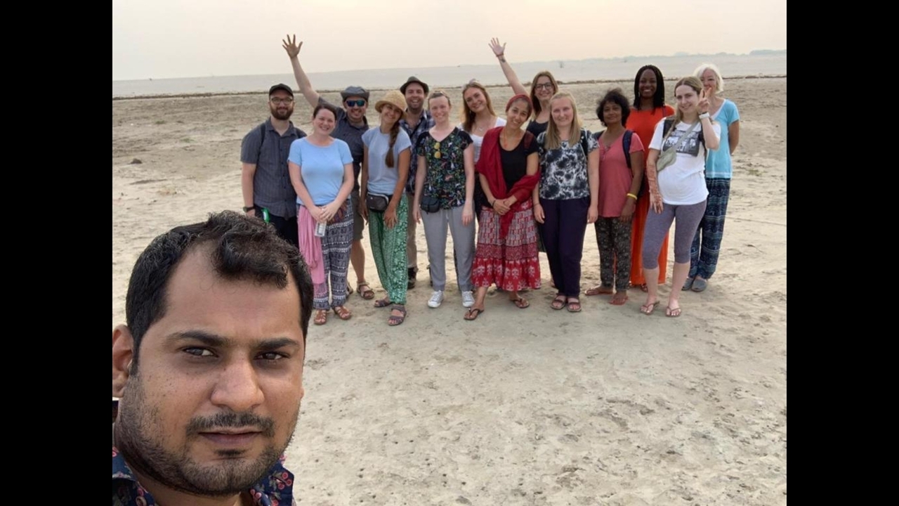 Groupe de personnes qui posent sur une zone sablonneuse.