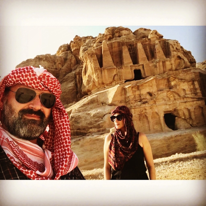 Deux personnes portant des foulards traditionnels devant d'anciennes structures rocheuses.