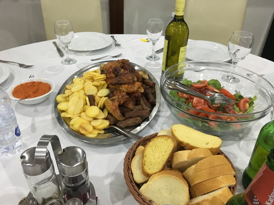 Table dressée avec des plats de cuisine traditionnelle incluant du pain, de la salade et des viandes.
