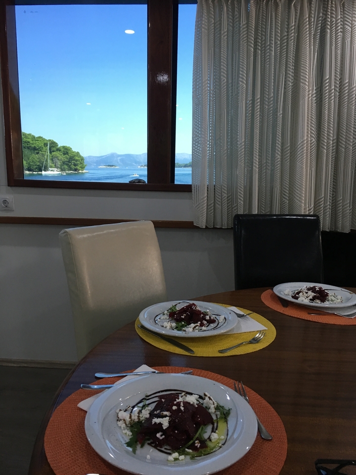 Table à manger d'intérieur dressée avec des assiettes et vue sur une baie par la fenêtre.