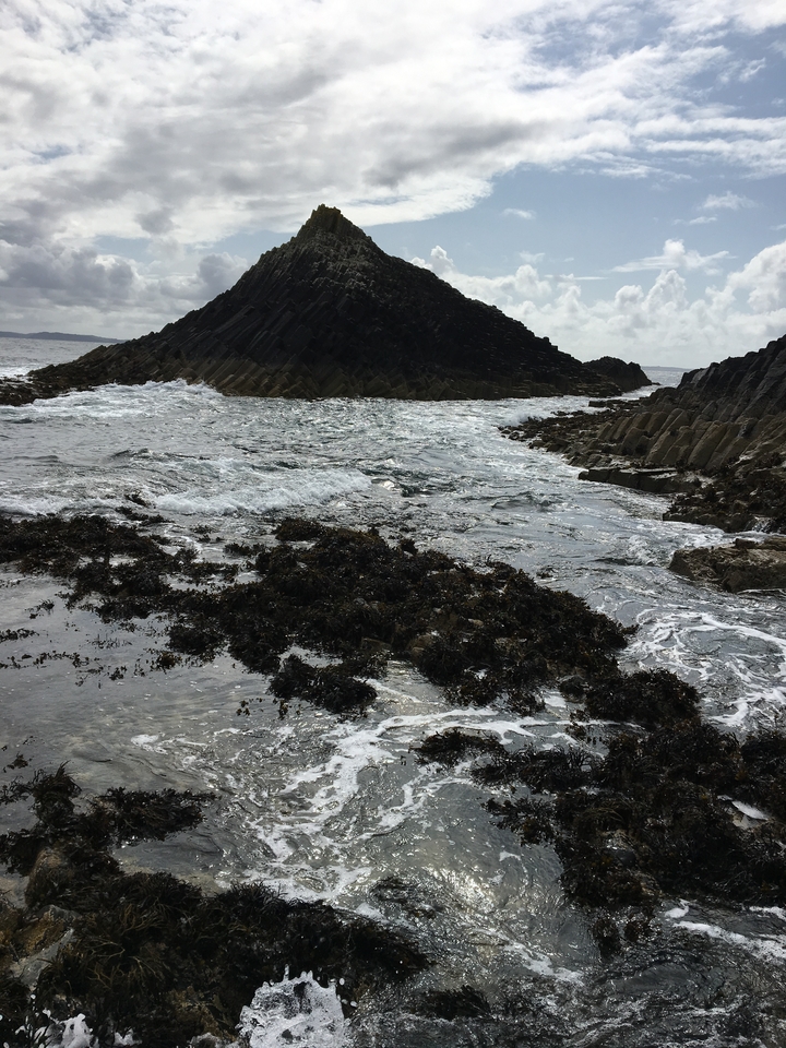 Un rivage rocheux avec des formations géologiques uniques et des vagues.