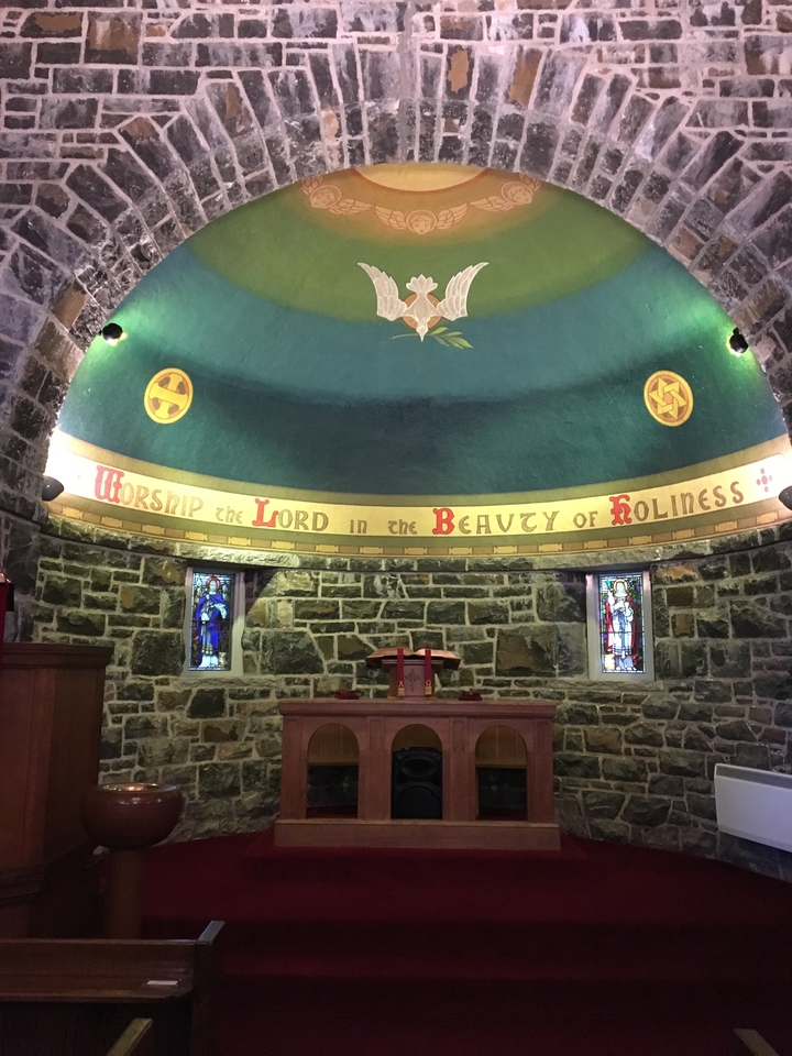 Intérieur d'une chapelle avec des vitraux et des murs de pierre.