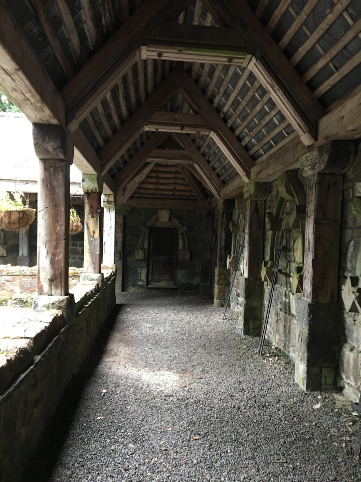 Un vieux couloir de pierre ombragé avec des poutres en bois.