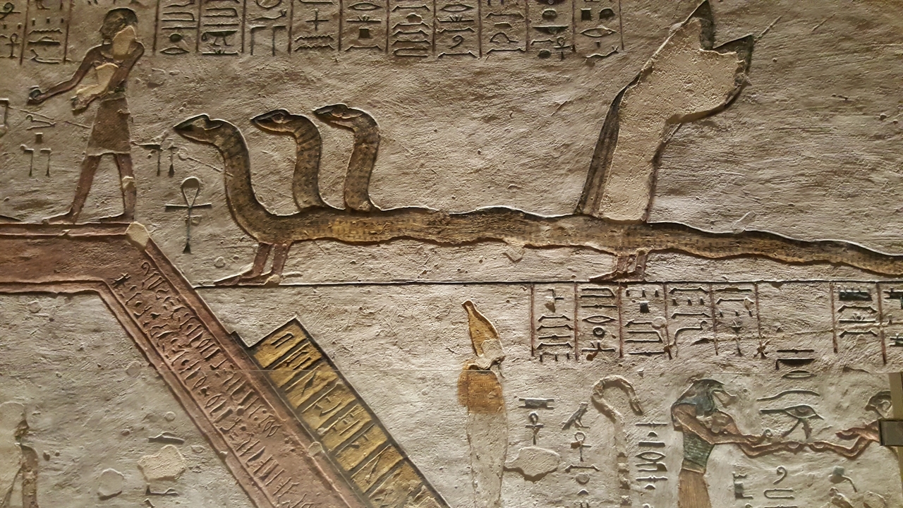 Art mural égyptien antique représentant des serpents et des symboles.