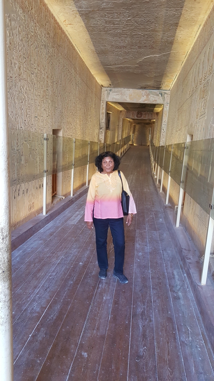 Personne marchant dans un couloir décoré d'hiéroglyphes anciens.