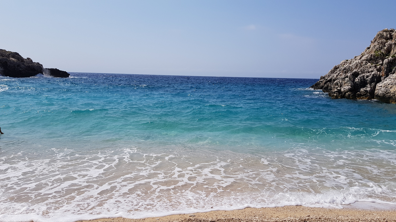 Des vagues bleues et limpides de l'océan qui se brisent sur une plage de sable.
