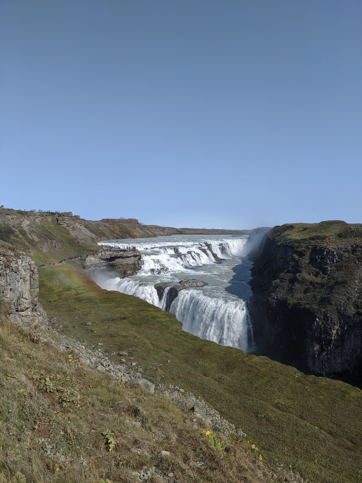 Massive waterfall with multiple tiers and visitors on the path.