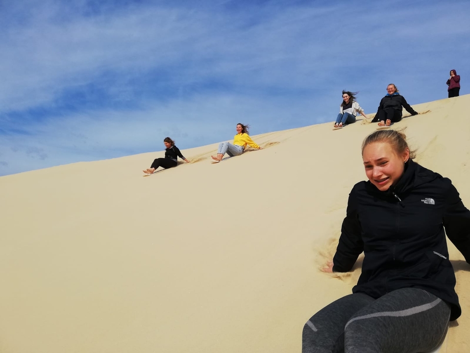 Des gens qui glissent le long des dunes de sable.