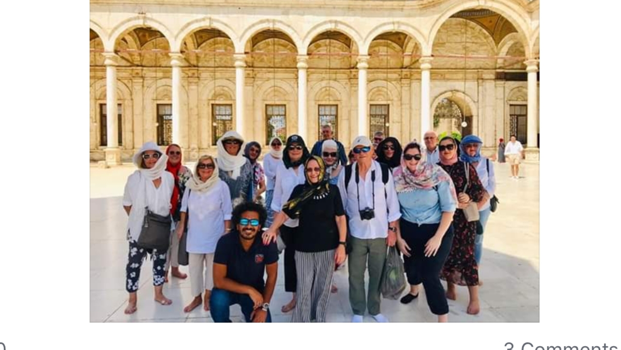 Group of people posing in front of an architectural structure.