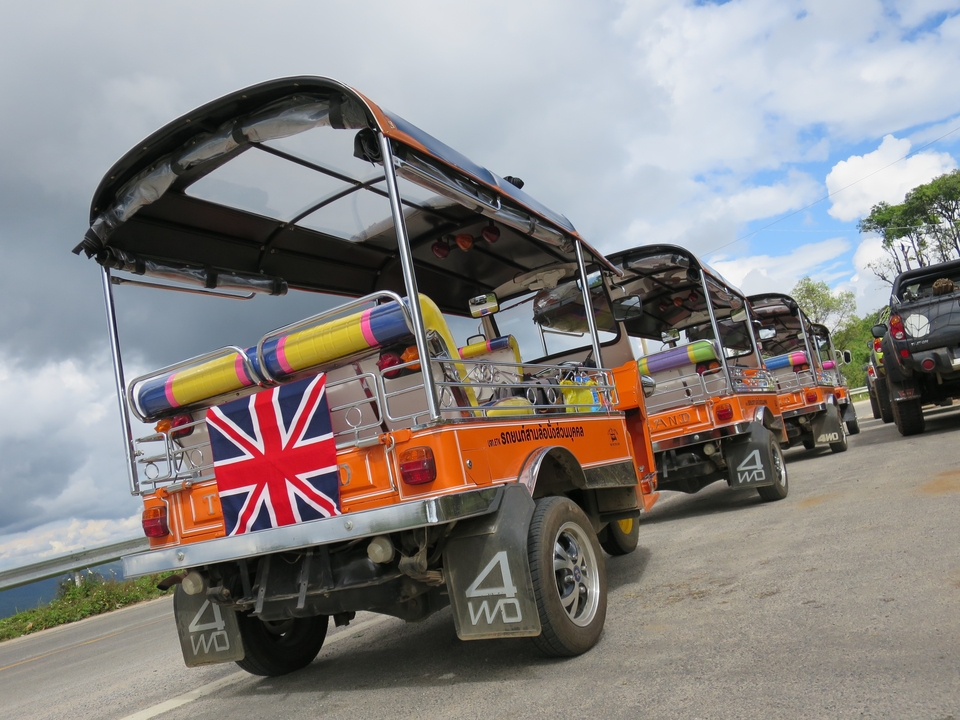 Véhicules tout-terrain avec des coussins Union Jack garés en ligne, contre un ciel nuageux.