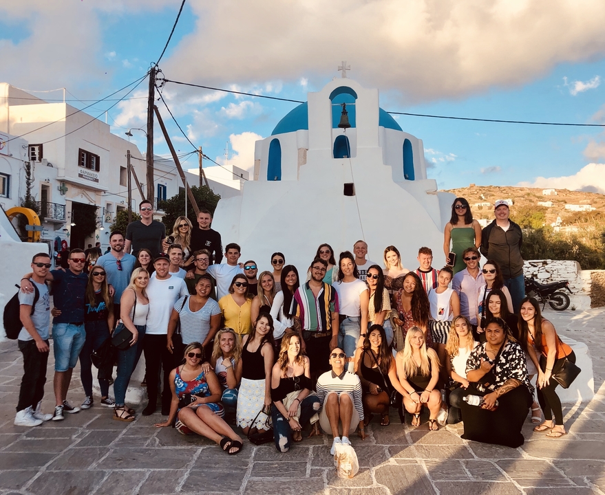 Large group of people posing in front of a blue-domed church.