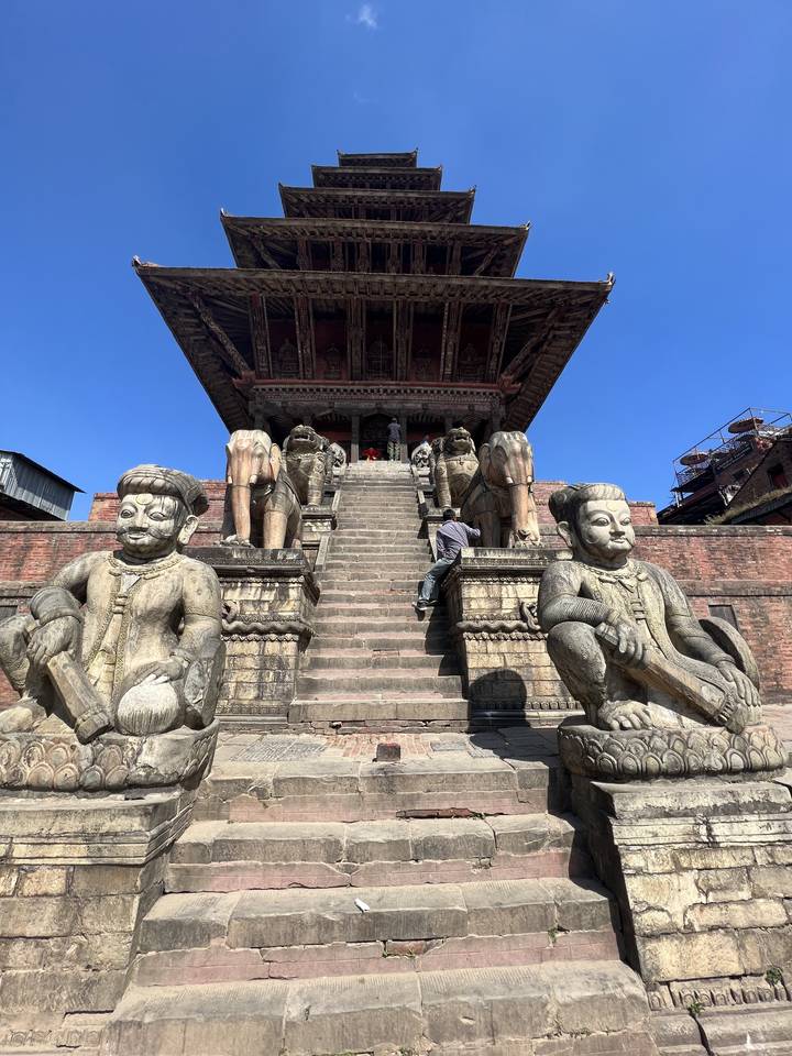 A temple staircase with stone statues and people.