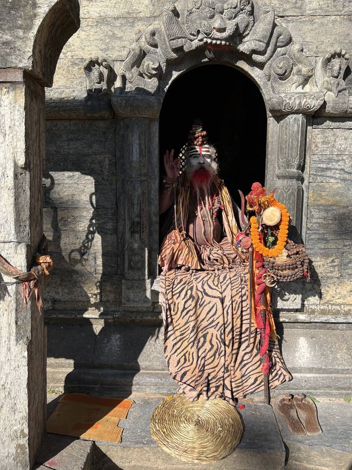 A person in traditional attire at a stone entrance.