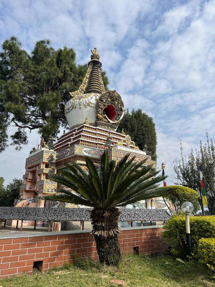 A side view of a decorated stupa with greenery.