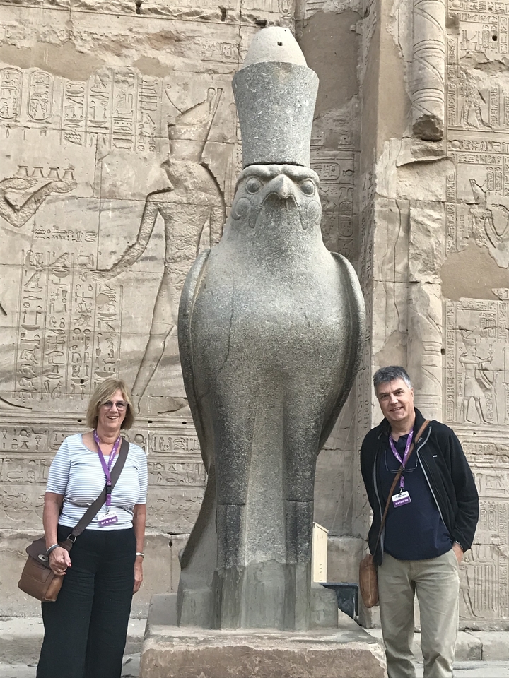 Des touristes posant avec une statue d'Horus.