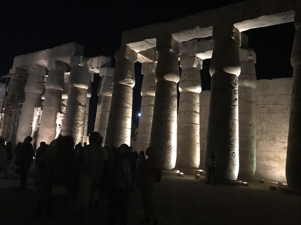 Temple ancien illuminé la nuit avec des visiteurs.